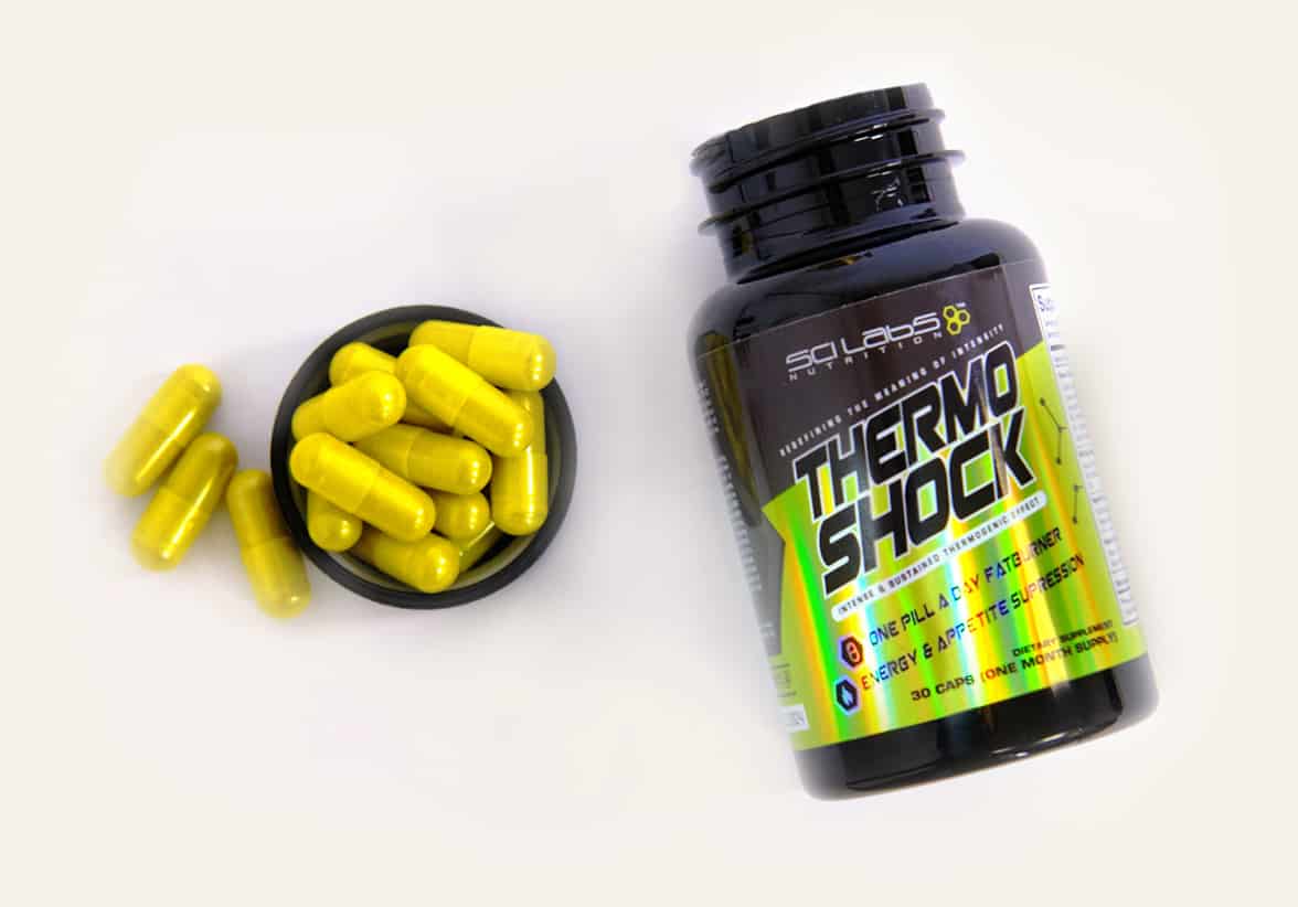 Bright yellow supplements laying next to an open bottle with a holographic label.